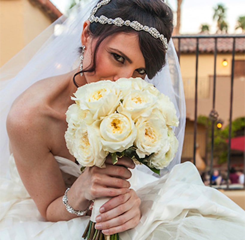 Bride with white rose bouquet on the terrace at golden hour